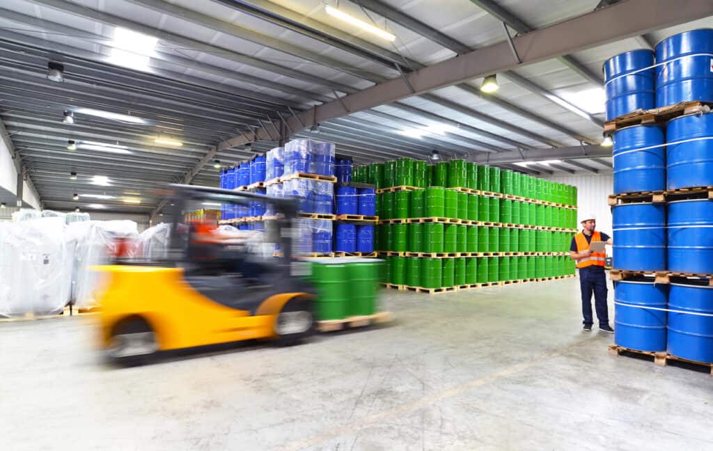 group of workers in the logistics industry work in a warehouse with chemicals - lifting truck